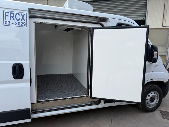 Furgone refrigerato bianco con sportello laterale aperto che mostra l'interno del vano di carico vuoto.