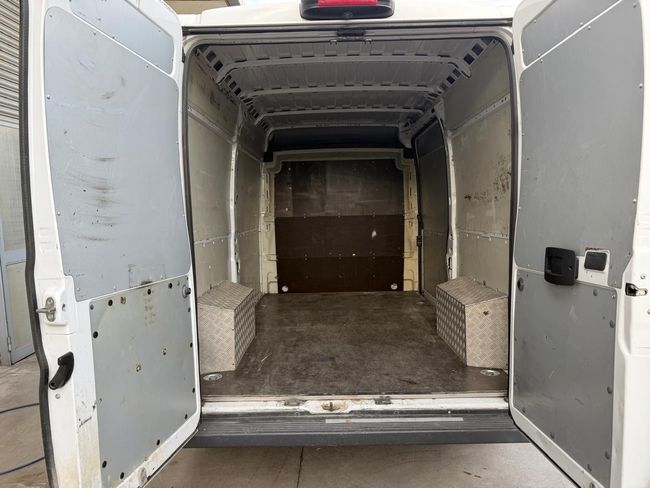 Interno vuoto di un furgone bianco con portelloni posteriori aperti e pavimento in metallo.