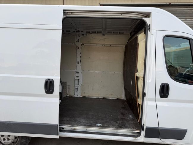 Furgone bianco con portellone laterale scorrevole aperto, che mostra un vano di carico interno vuoto.
