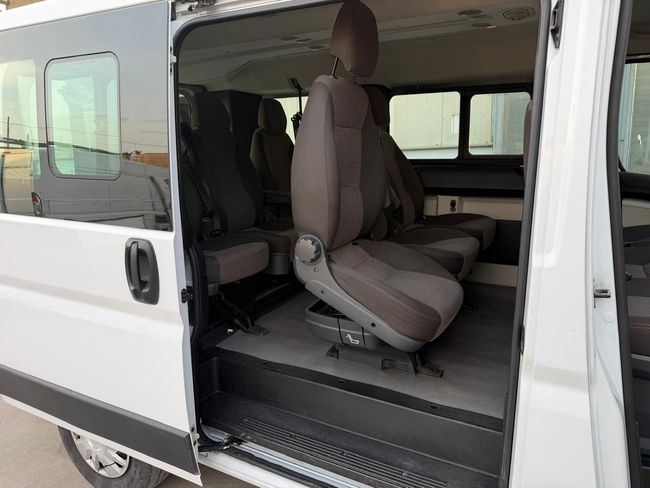Interno del furgone bianco a vista con sedili grigi ripiegabili e pavimento accessibile.
