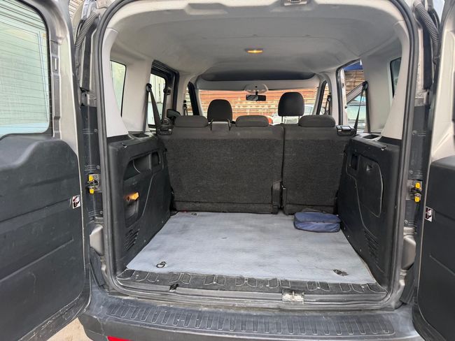 Furgone aperto con sedili posteriori ripiegati e vano di carico vuoto rivestito di moquette.