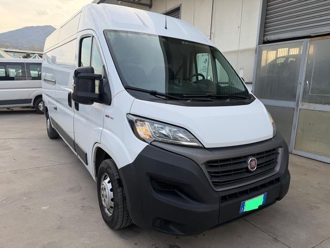 Furgone bianco parcheggiato all'aperto vicino a un edificio, vista frontale sinistra.
