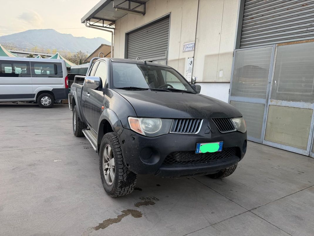Un pick-up nero parcheggiato vicino alla banchina di carico di un magazzino, con un furgone bianco sullo sfondo.