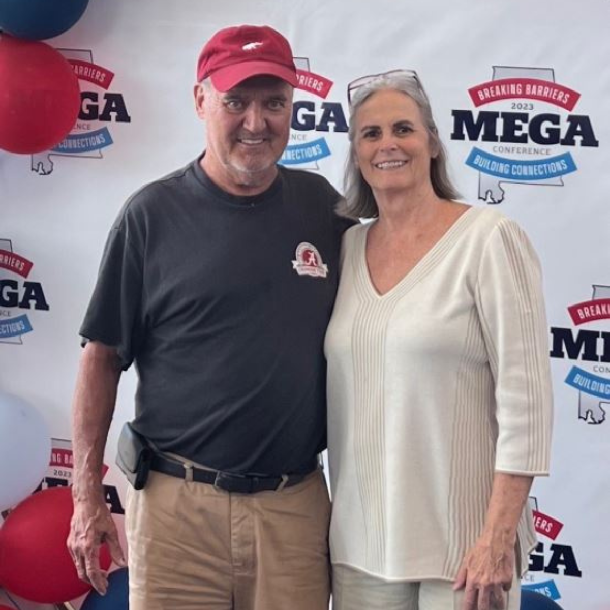a man and woman pose in front of a mega sign