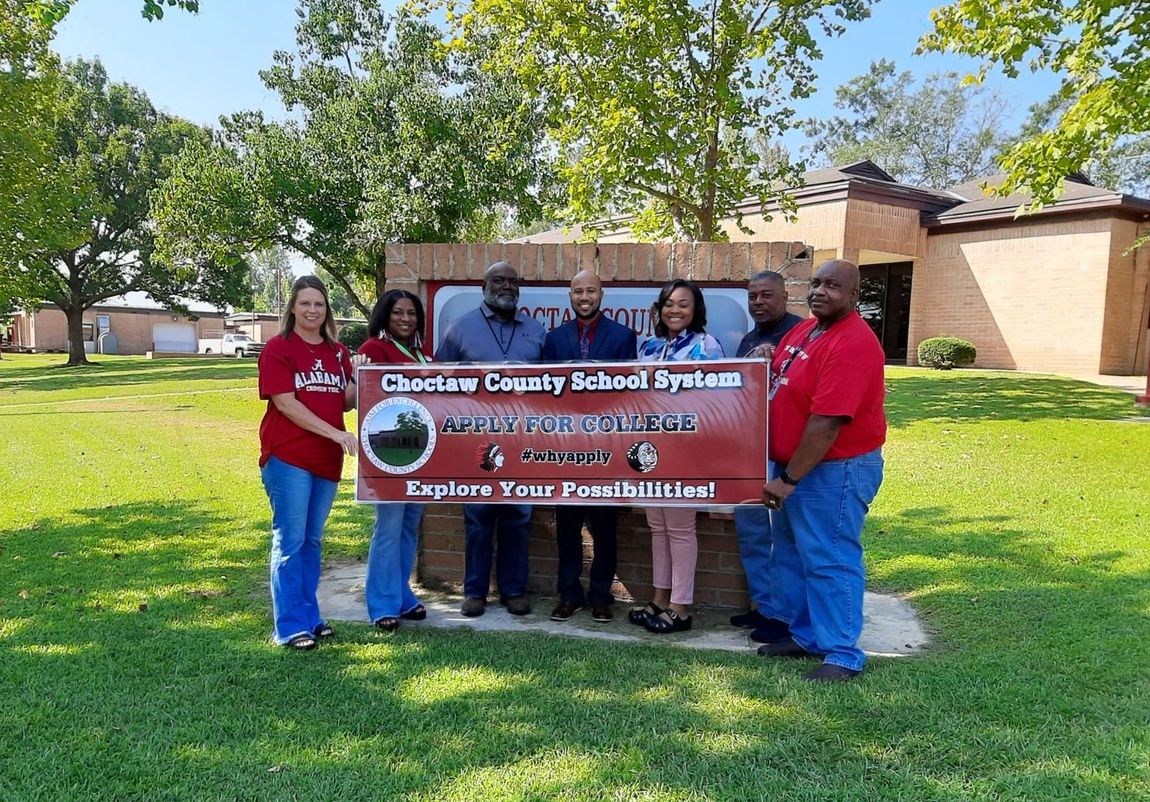a group of people standing in front of a sign that says cheetah county school system