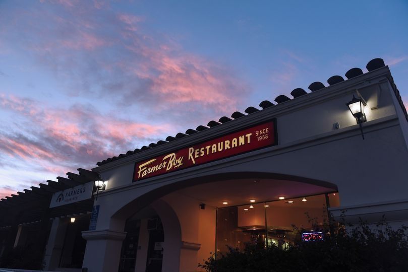 Restaurant entrance at dusk with red sign and arched doorway under a pink-blue sky