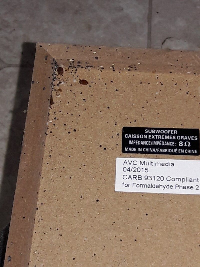 Close-up of a subwoofer corner with a label showing specifications and formaldehyde compliance.