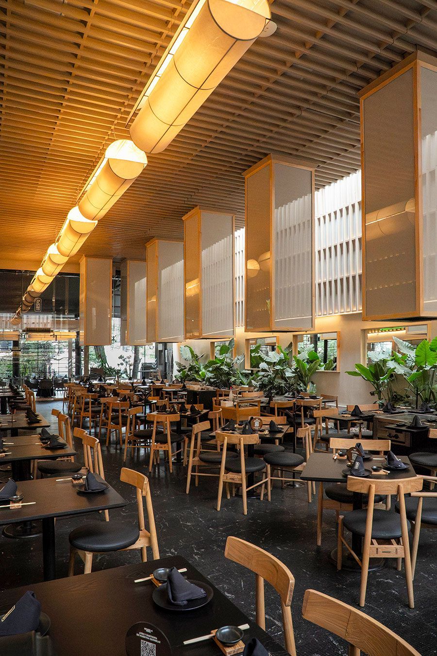 Interior acogedor de una cafetería con mesas de madera, bancos rojos y decoración de pared ornamentada.