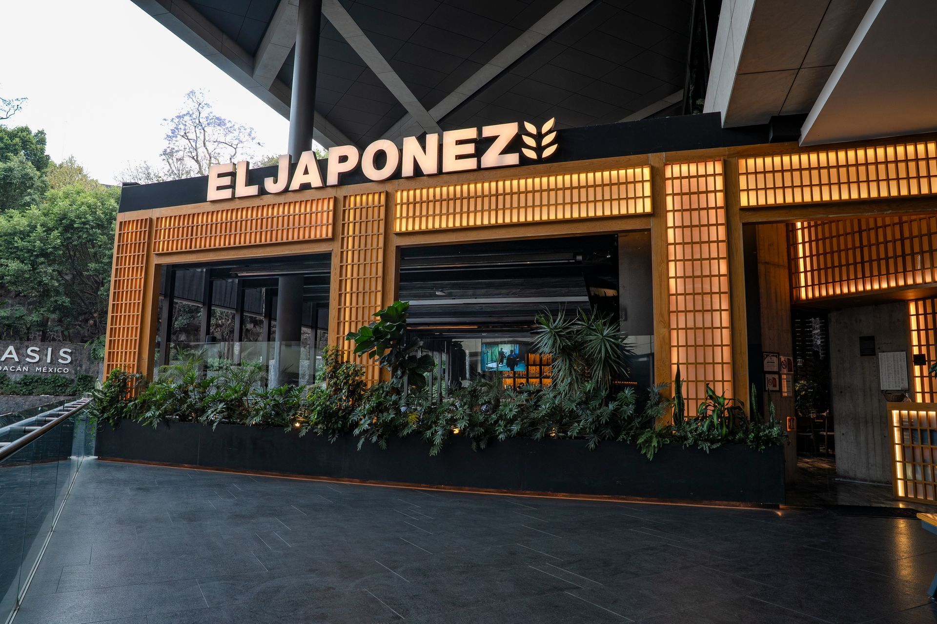 Exterior del restaurante El Japonez con cálida fachada de madera y letrero luminoso al anochecer.