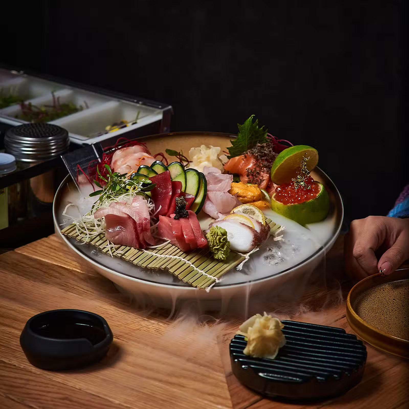 Plato de sushi y sashimi con limón, caviar y guarnición en una mesa de restaurante.