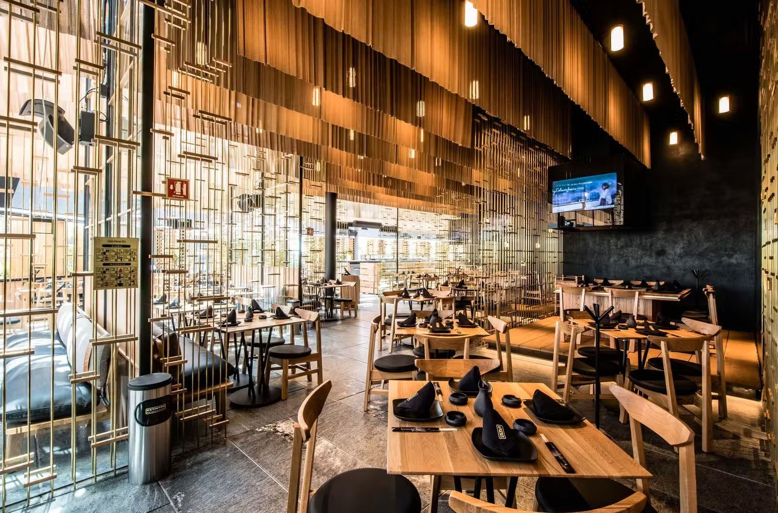 Comedor moderno: mesas madera, sillas y muro verde.