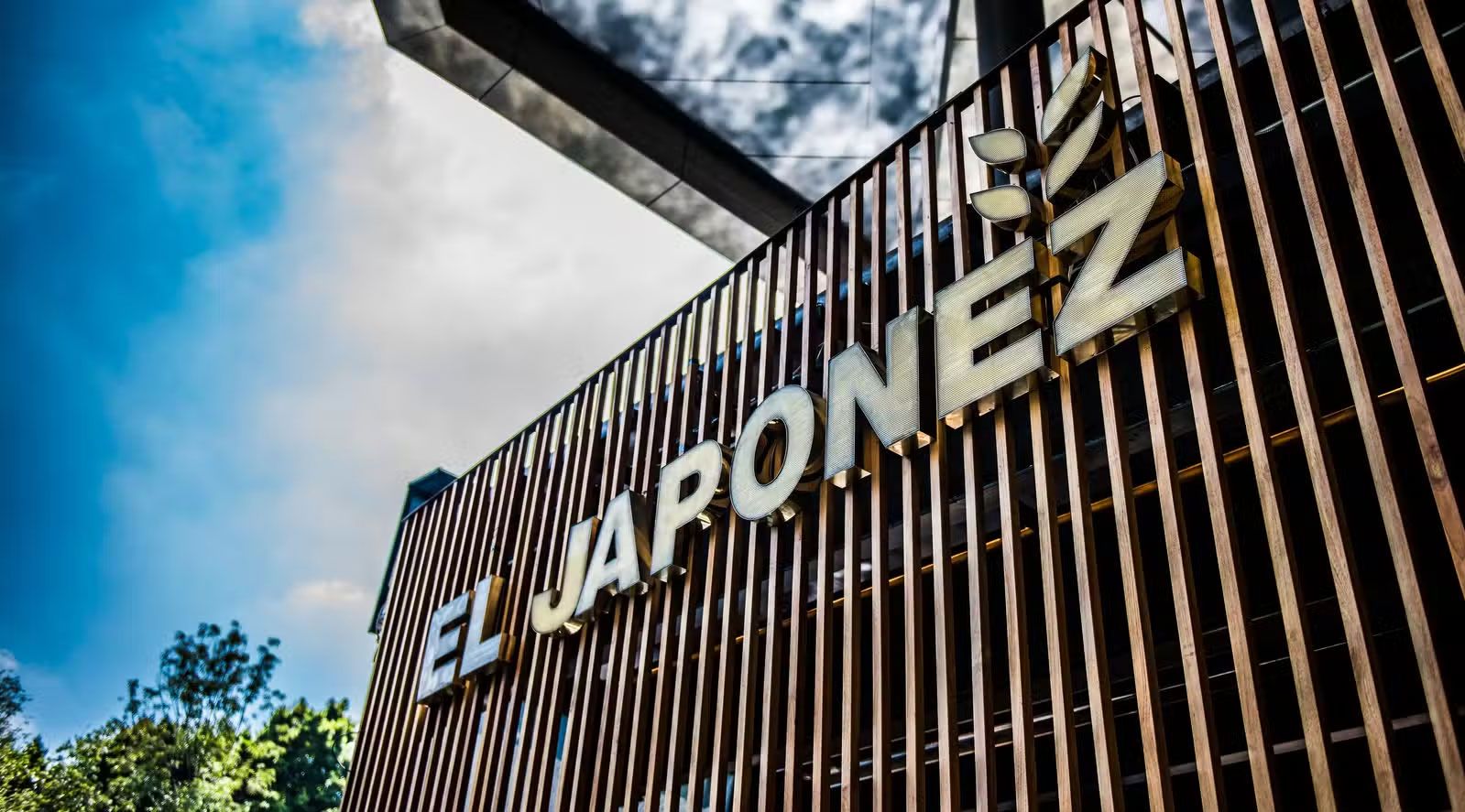 Letrero con la inscripción “EL JARONEZ” en un moderno edificio de listones de madera contra un cielo azul.