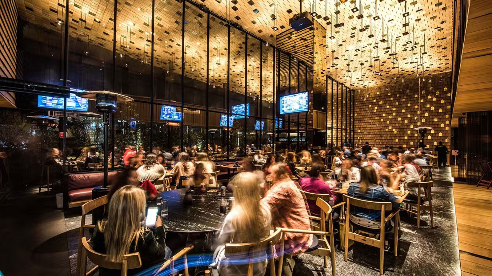 Restaurante abarrotado con luces de guirnalda cálidas y comensales sentados en mesas, visto desde un acogedor patio interior.