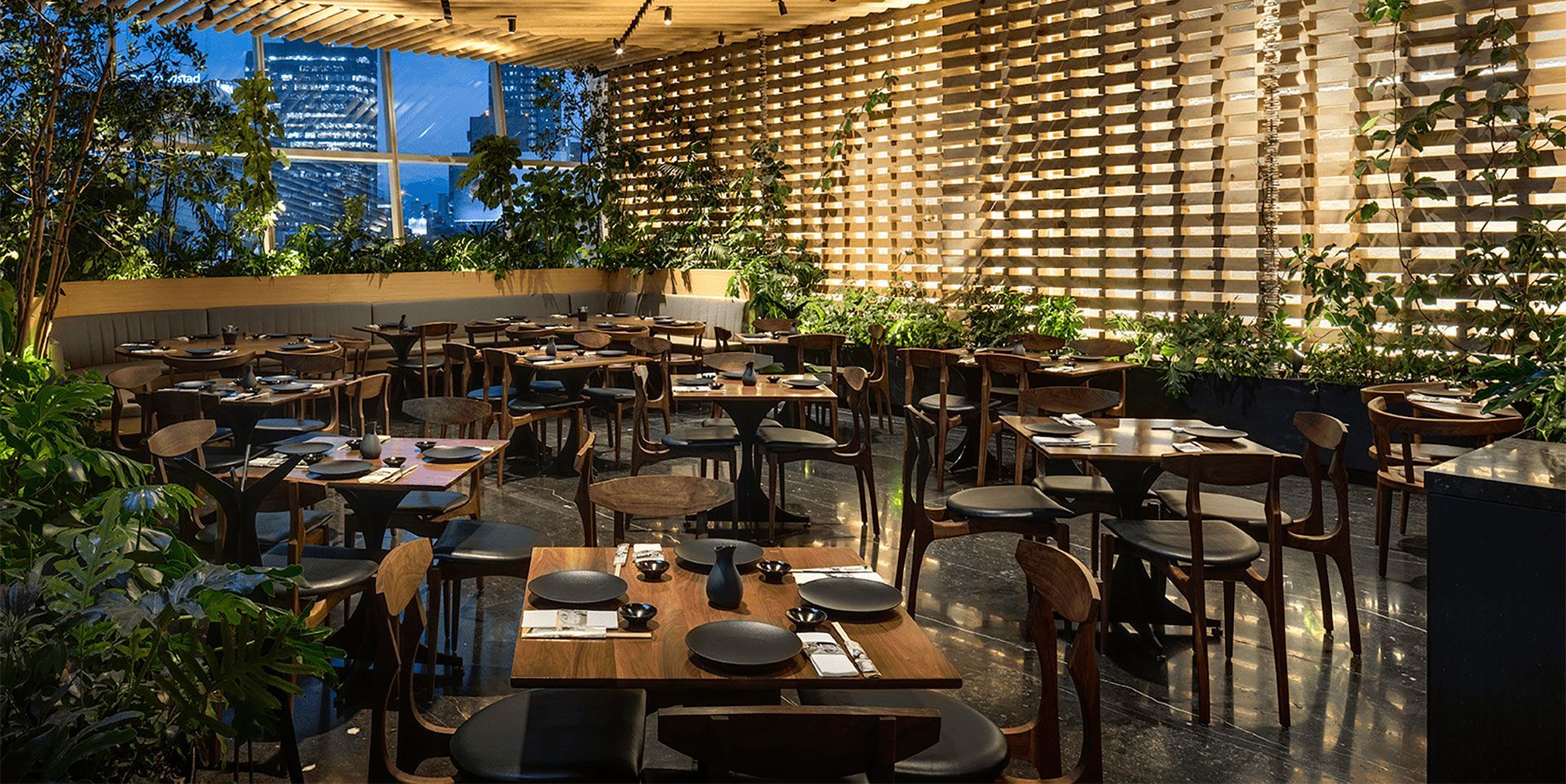 Patio acogedor con madera, mimbre y mucha vegetación.
