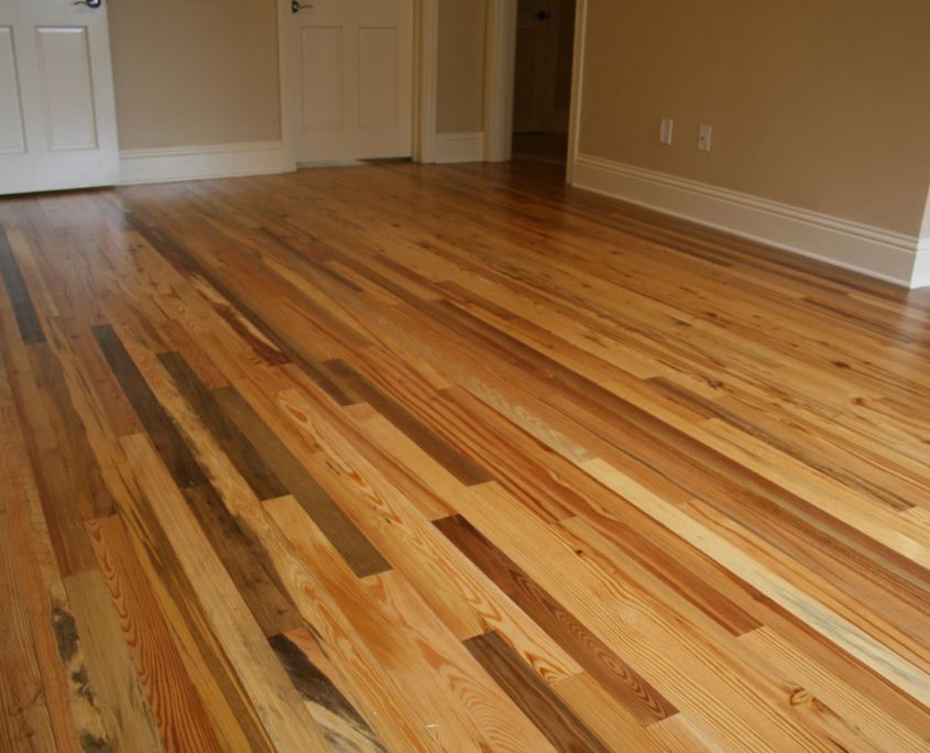 Wooden floor in a room with light beige walls and white doors.