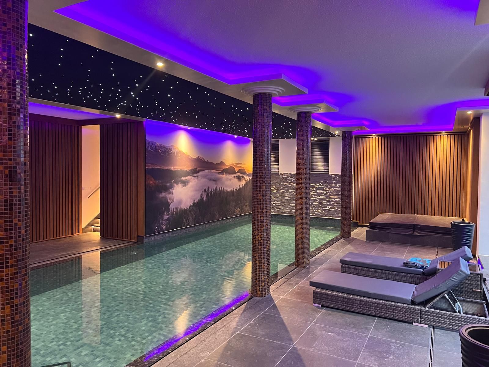Sfeervol zwembad met kleuren led strips ,stijlvolle wandprint en twinkelende sterrenhemel in akoestisch spanplafond.