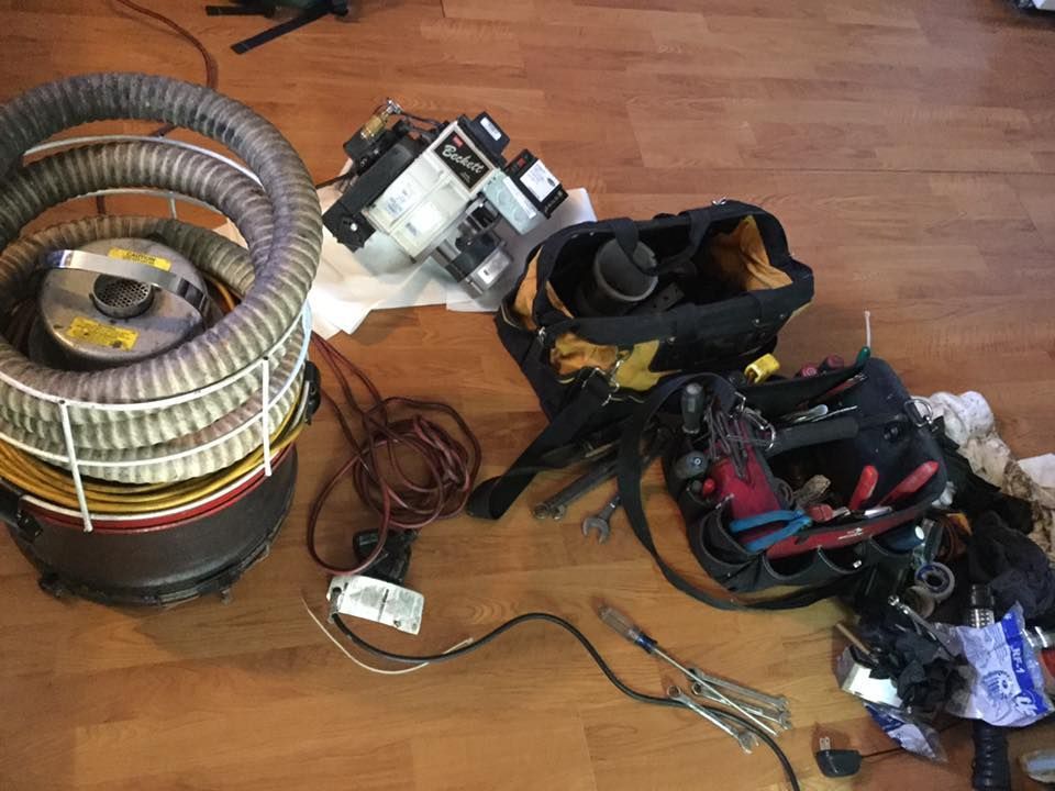 Assorted electrical parts, wires, and tools spread on a wooden floor.