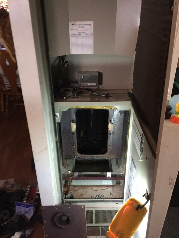 Open wall HVAC/air handler cavity with exposed ductwork and tools in a hallway.