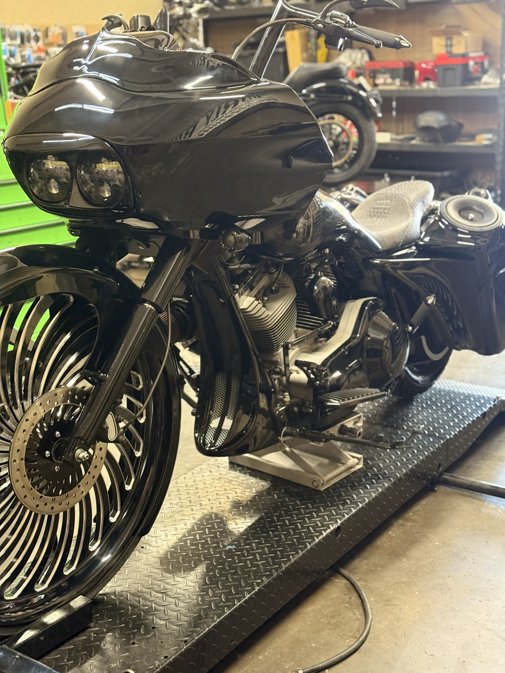 Black custom motorcycle with chrome wheels on a display platform in a workshop