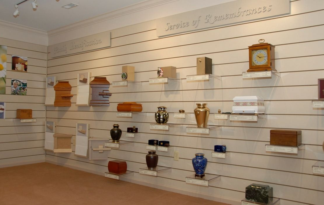 Wall display of handcrafted clocks and small decorative items on white slatwall shelves in a store.