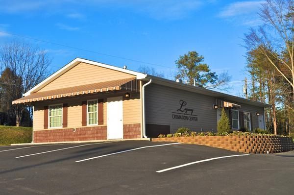 Single-story brick office building with tan siding and landscaped parking lot on a sunny day