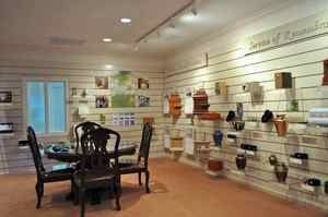 Bright retail showroom with white slat walls displaying items and a dark dining table with chairs in the center