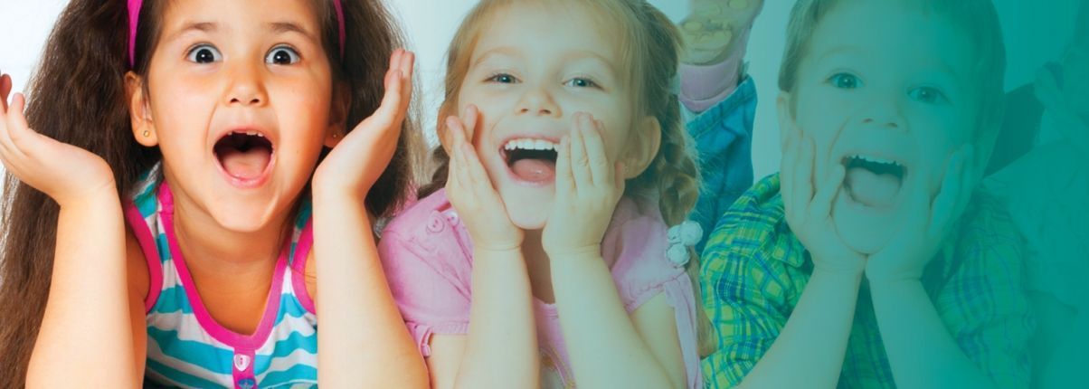Three young girls smiling with their hands on their faces.