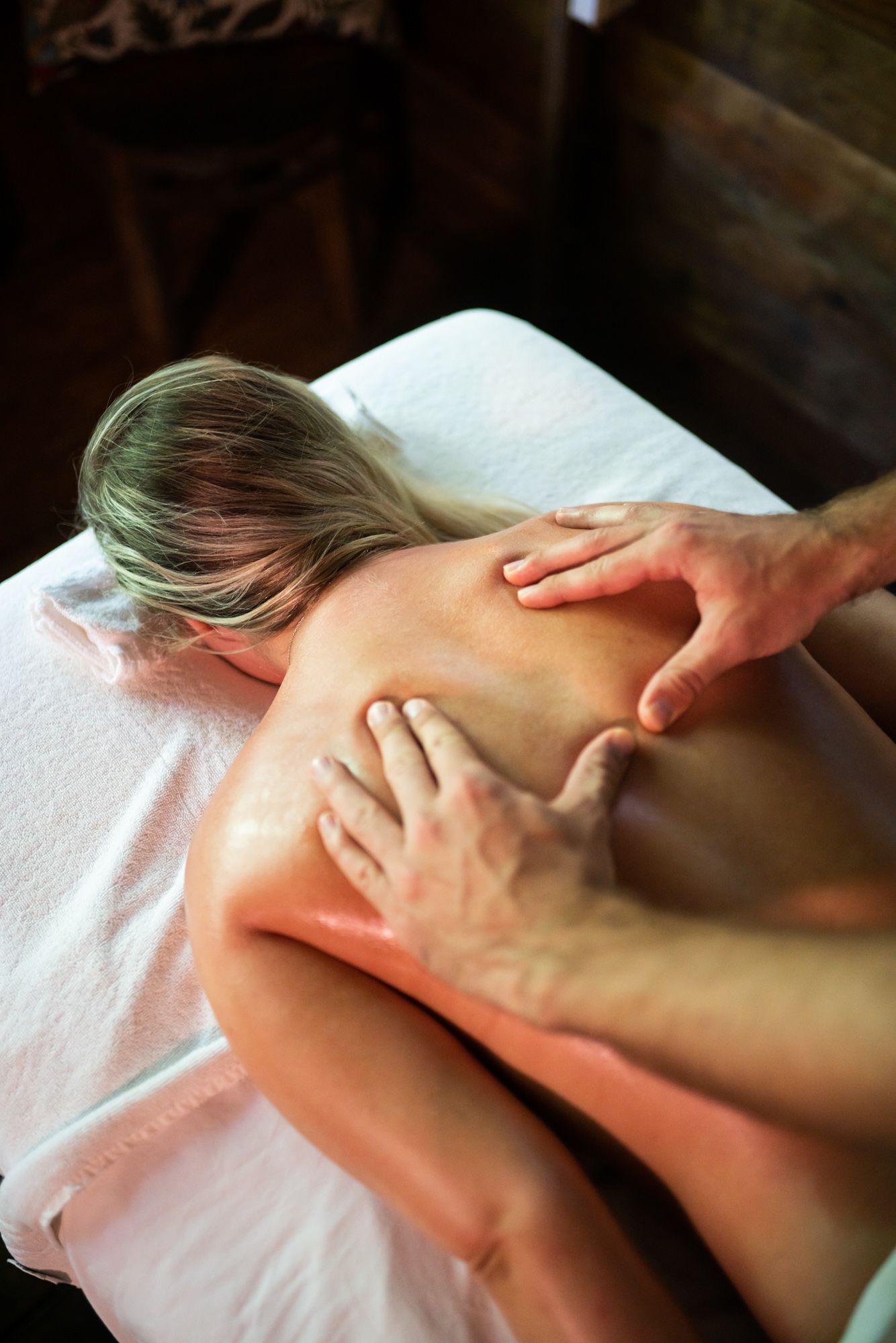 Massage therapist kneading a person's back on a massage table in a spa setting