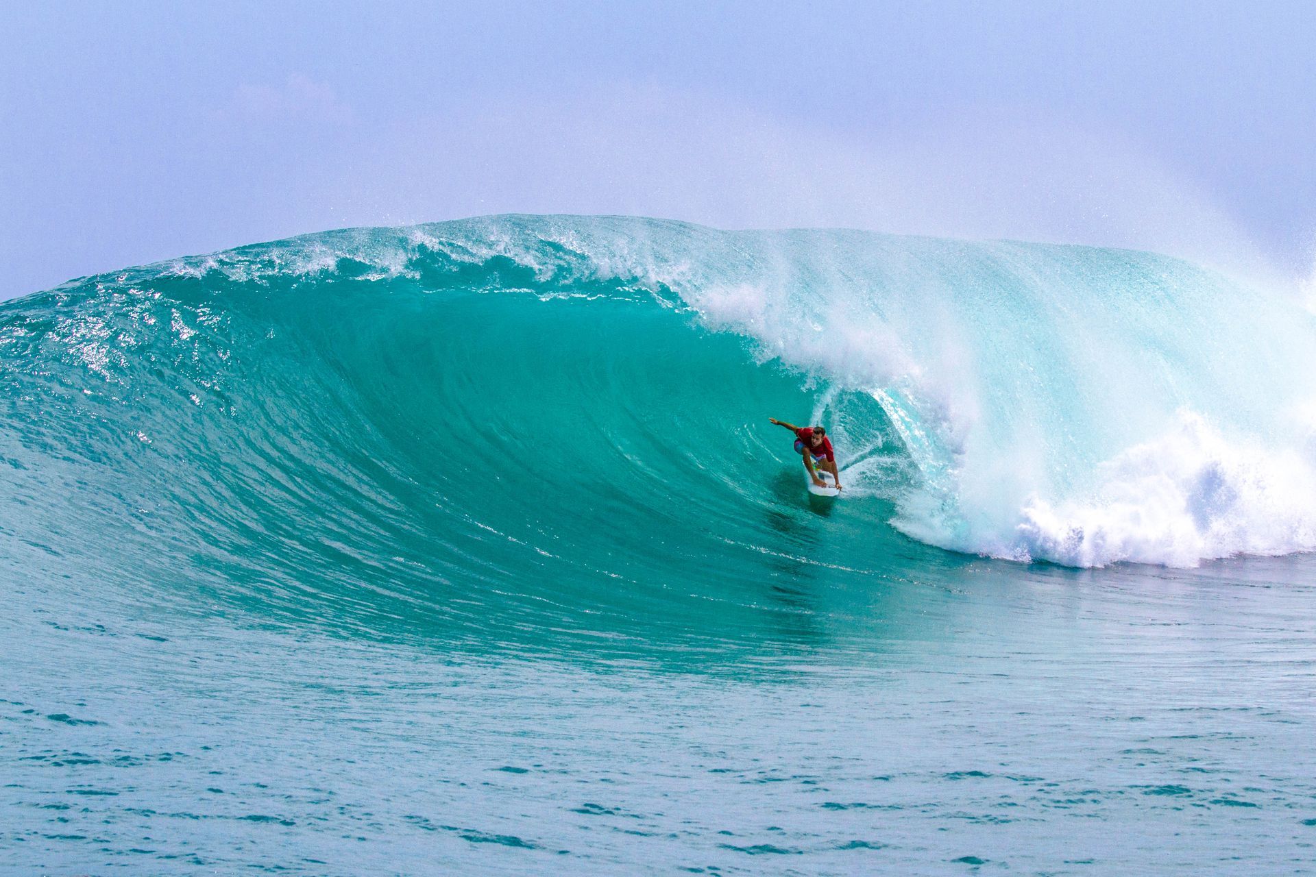 Surfer riding inside a turquoise wave near the shore