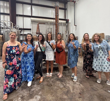 Tour group raising tasting glasses beside the copper still at Haleiwa Distilling Company in the historic Waialua Sugar Mill, North Shore Oahu