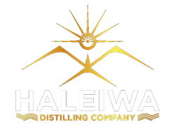 The haleiwa distilling company logo is a gold and white logo with a sun and mountains.