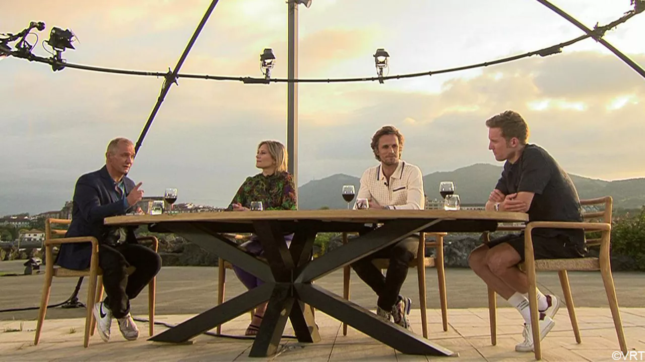 Four people seated at table outside, mountains in background, sunset.