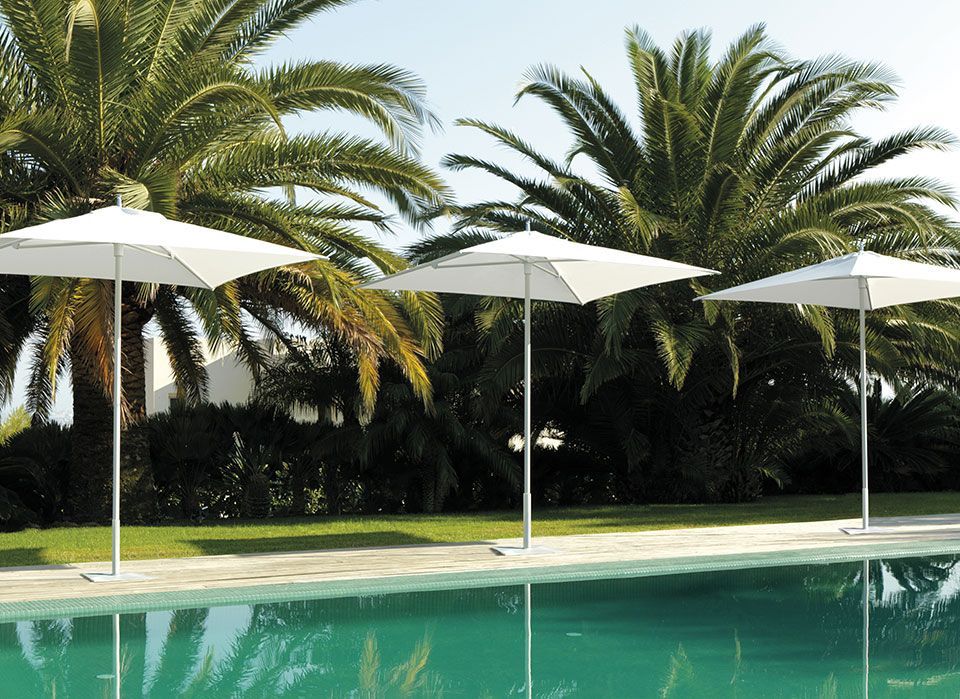 Three white square umbrellas by a turquoise pool, palm trees in the background.