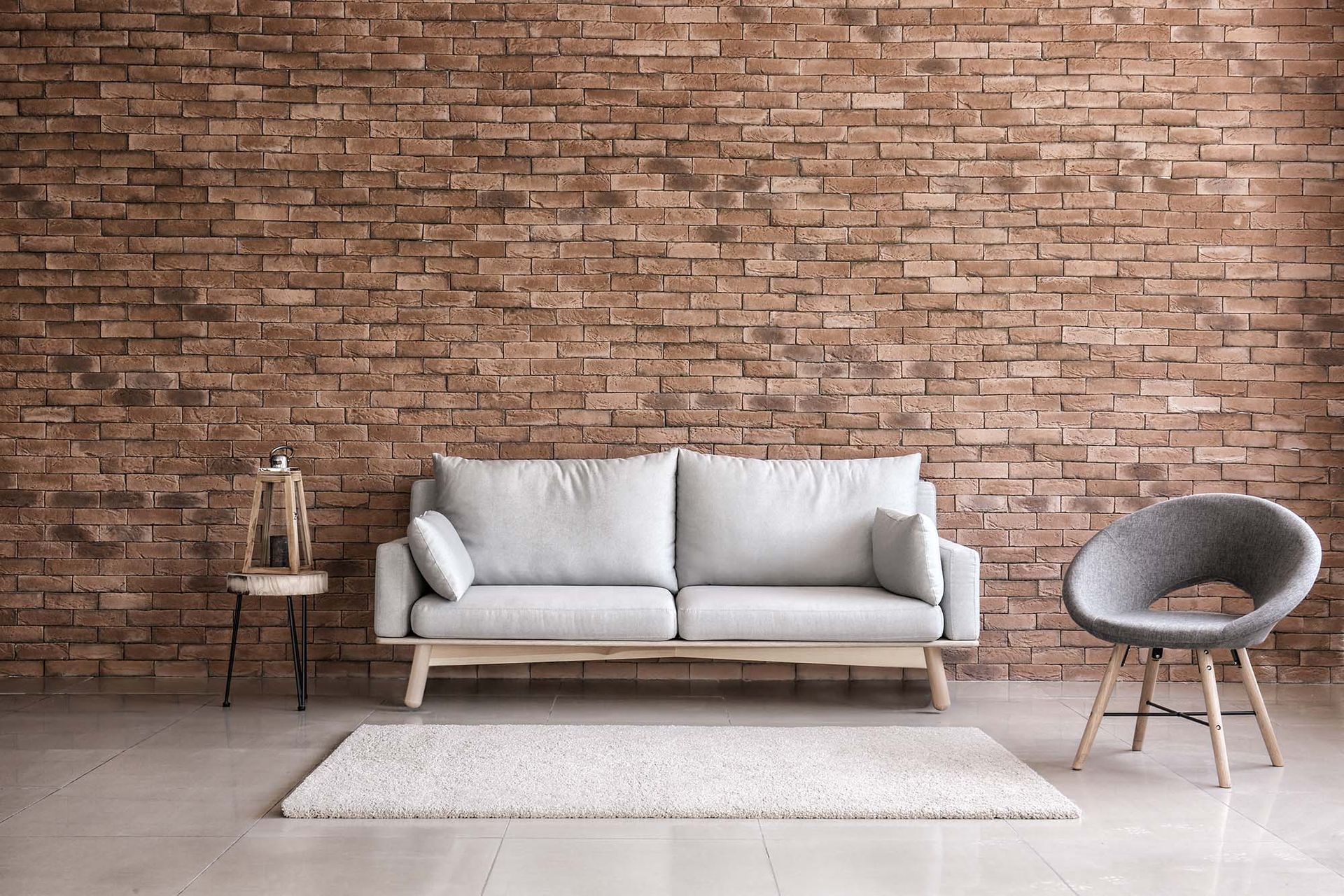 Minimal living room with gray sofa, round chair, rug, and brick accent wall