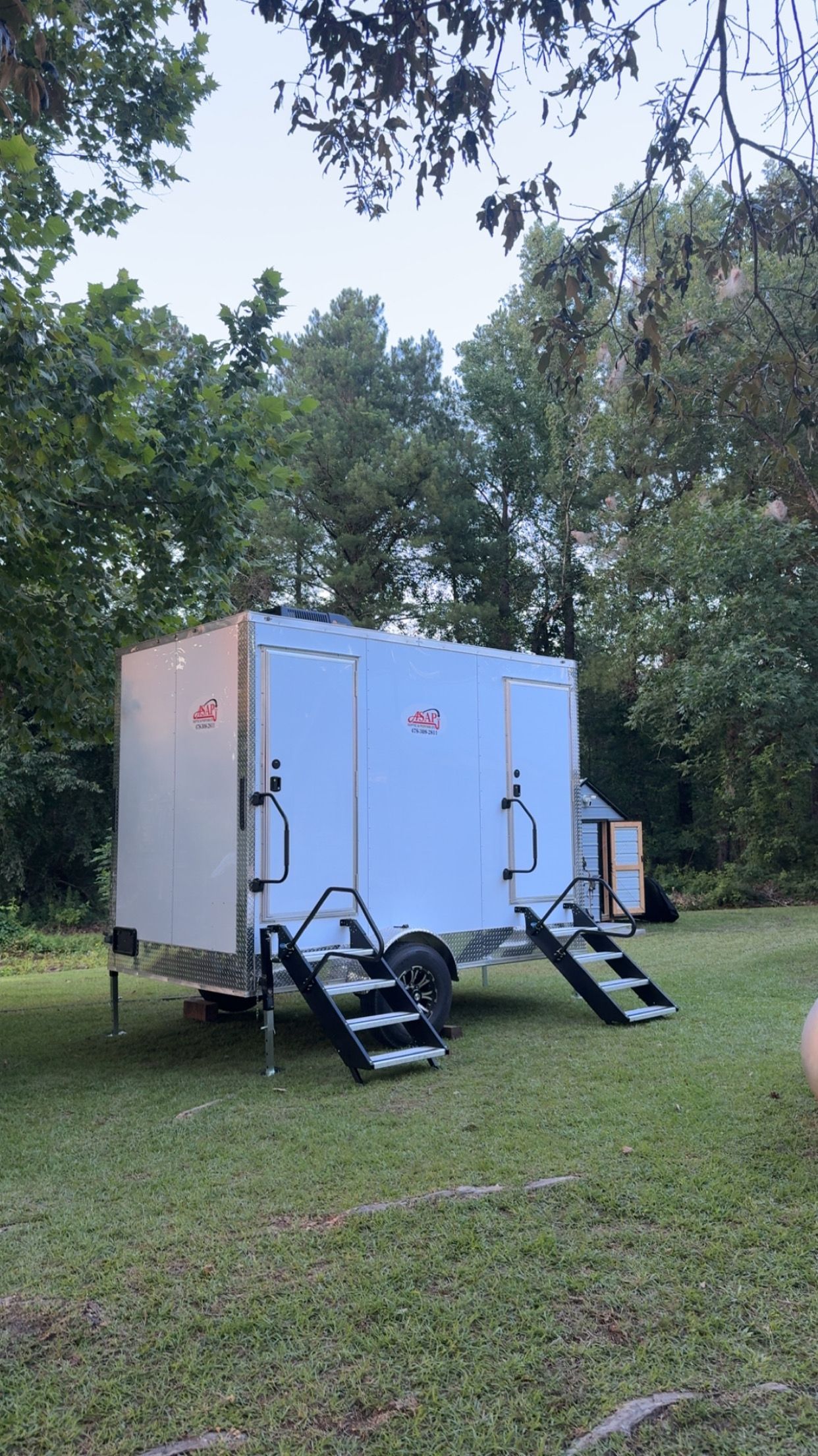 White trailer with a woman's restroom door and metal steps outside.