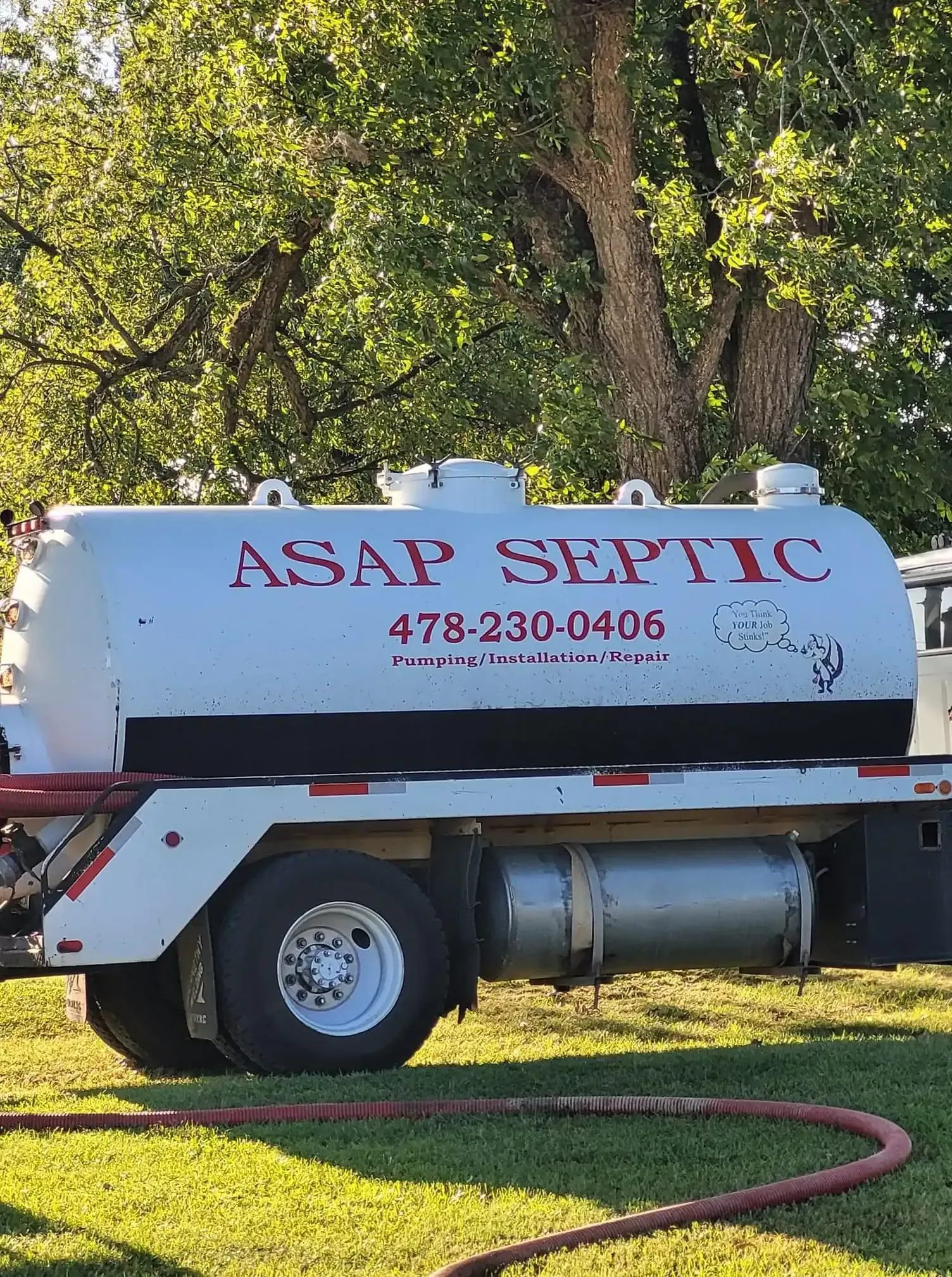 White septic service truck parked on grass with “ASAP SEPTIC” on the side and a hose in front.