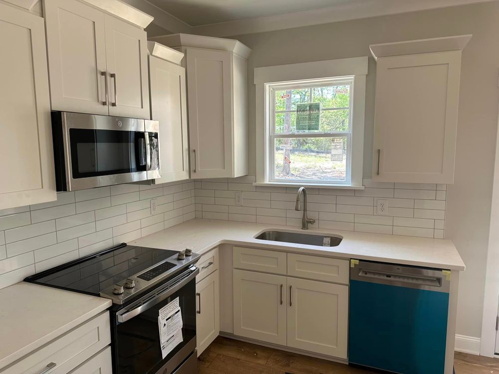 A kitchen with white cabinets , stainless steel appliances , and a blue dishwasher.