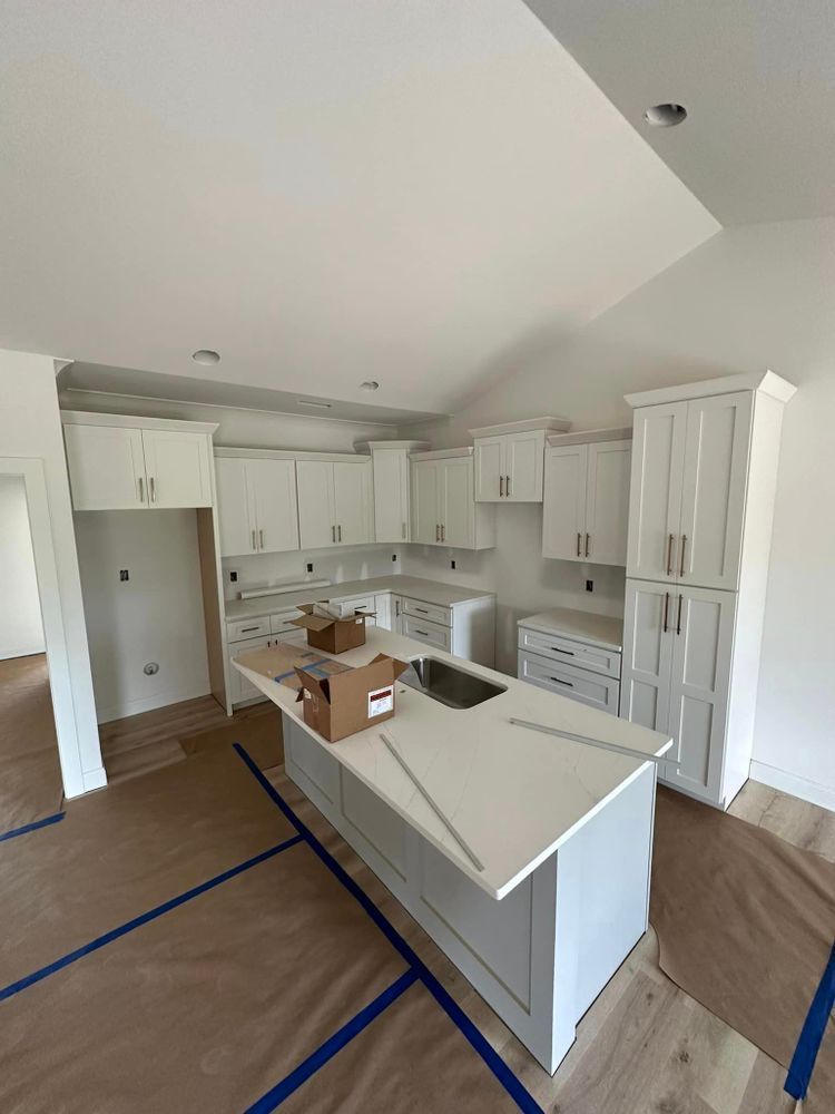 A kitchen with white cabinets and a large island in the middle