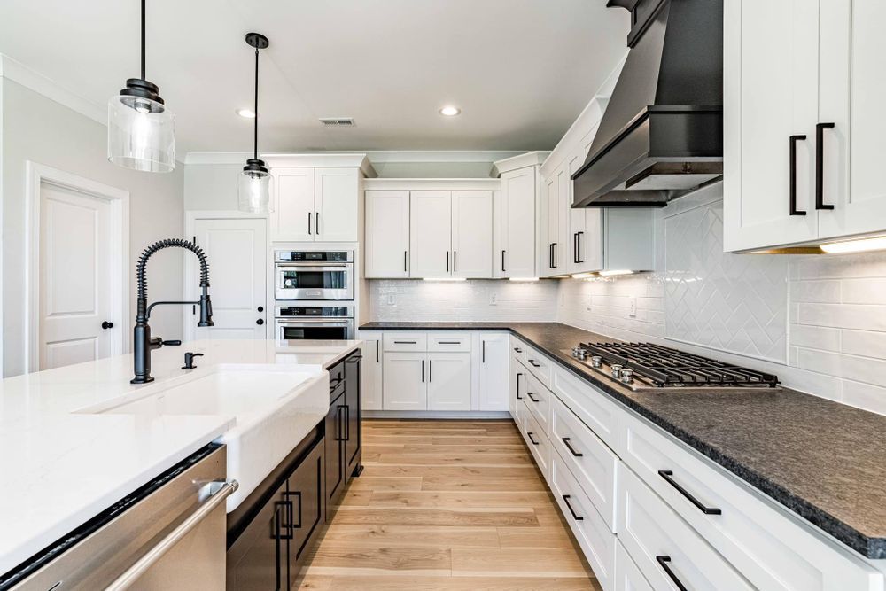 A kitchen with white cabinets , granite counter tops , stainless steel appliances and a sink.