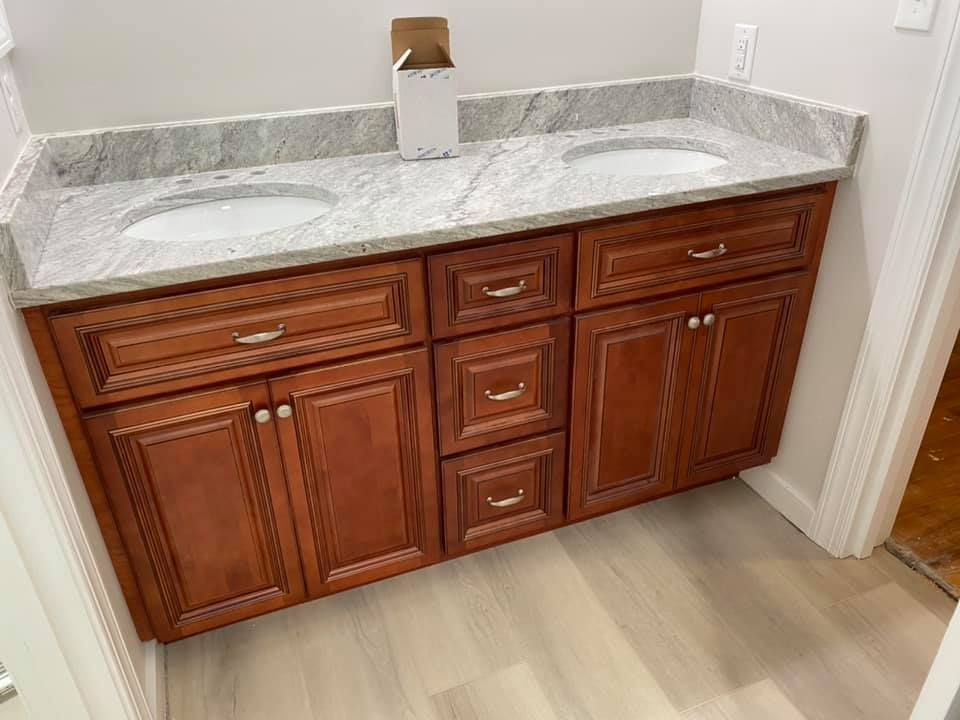 A bathroom vanity with two sinks and a marble counter top.