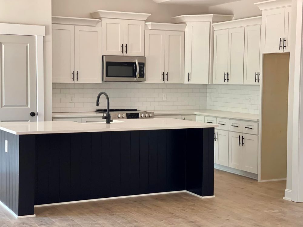 A kitchen with white cabinets and a black island.