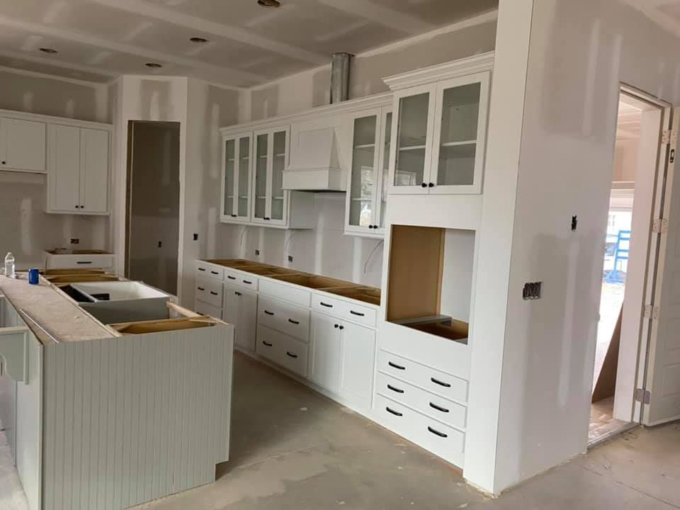 A kitchen under construction with white cabinets and a sink.