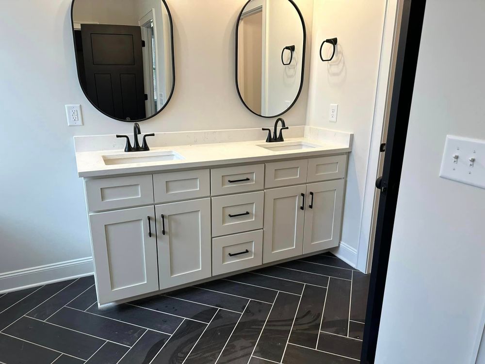 A bathroom with two sinks , two mirrors and a herringbone floor.