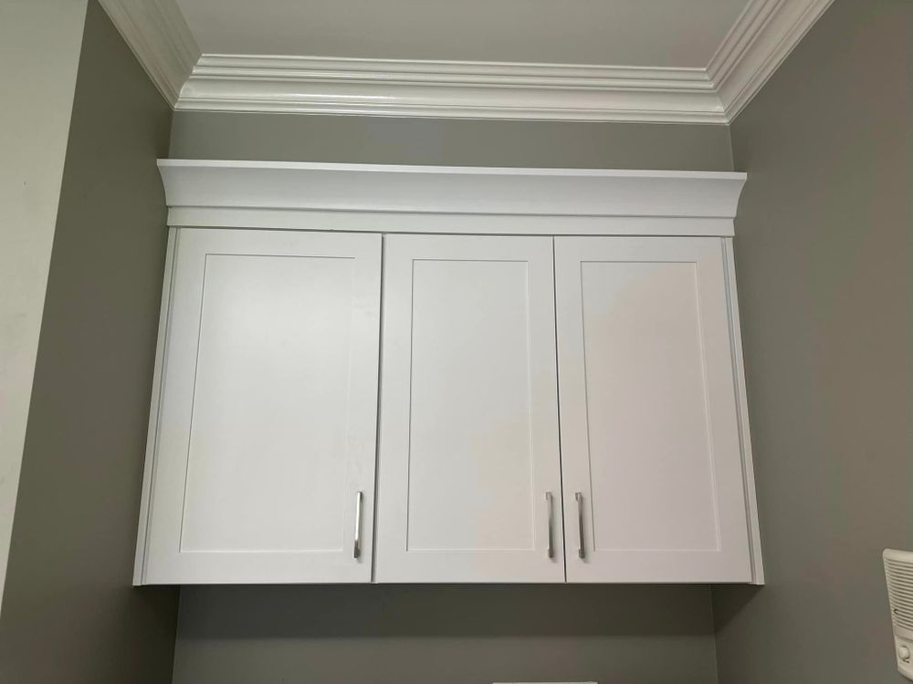 Three white cabinets are hanging from the ceiling in a room.