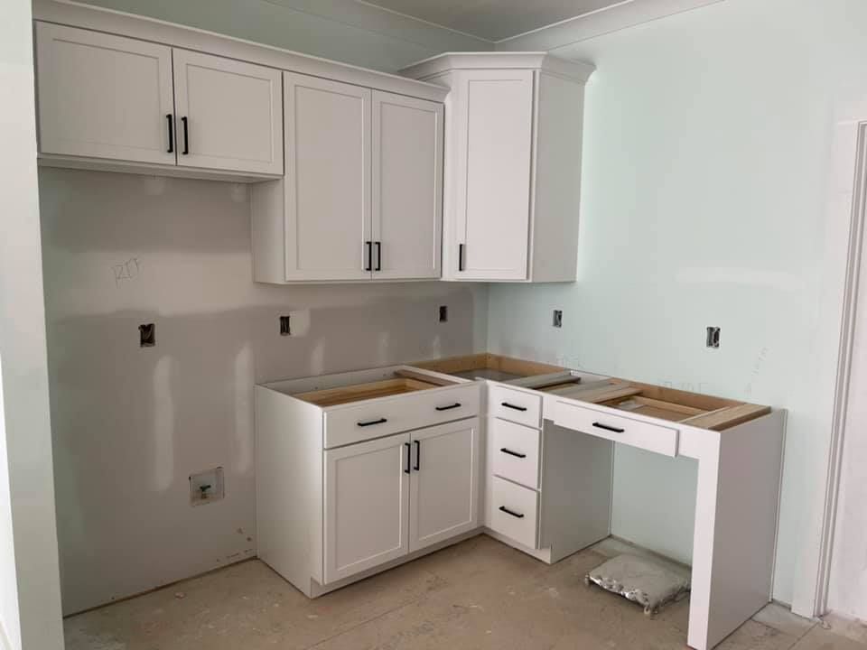 A kitchen under construction with white cabinets and a desk.