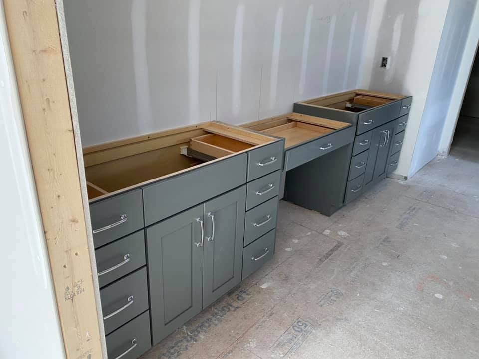 A kitchen under construction with gray cabinets and drawers.