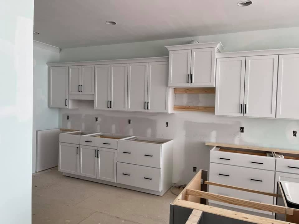 A kitchen under construction with white cabinets and drawers.