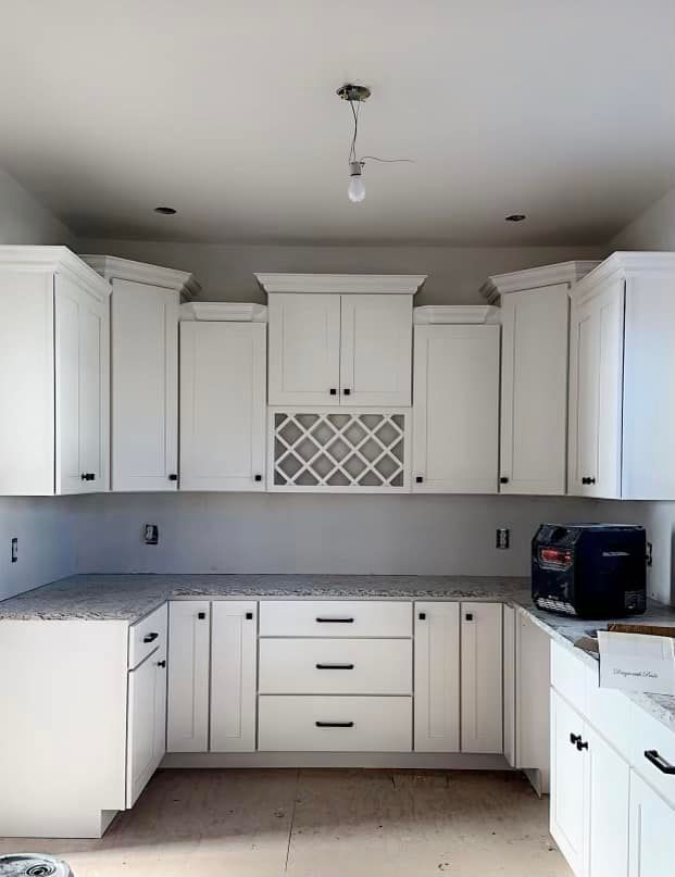 A kitchen with white cabinets and granite counter tops