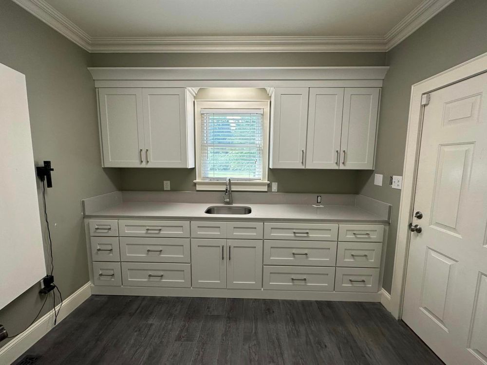 A kitchen with white cabinets , drawers , a sink and a window.