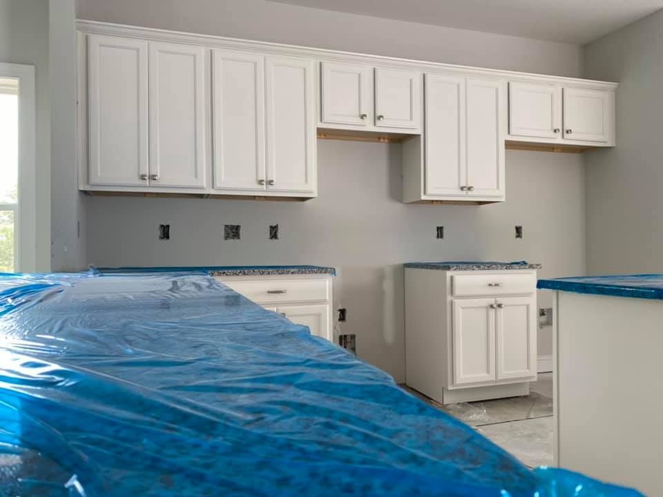 A kitchen with white cabinets and blue counter tops is being painted.